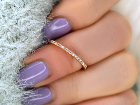 Close-up of a hand with a diamond ring and purple nail polish on a textured surface.