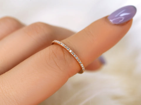 Rose gold ring with small diamonds on a finger with purple nail polish.