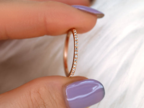Rose gold ring with diamonds held between fingers with purple nail polish on a white background