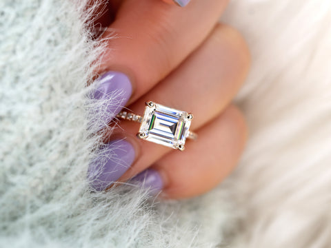 east west set emerald cut solitaire with diamonds on band on ring finger