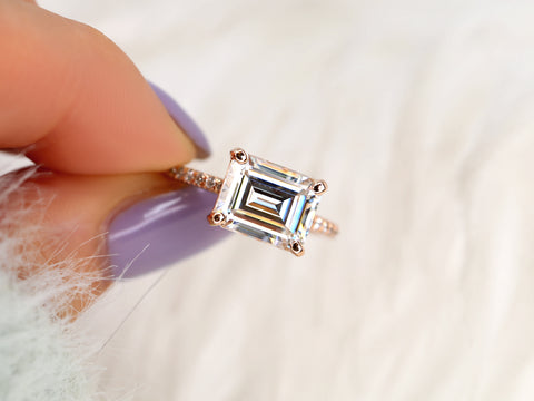 Rose gold ring with a large diamond held by a hand against a soft white background