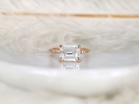 east west set emerald cut solitaire with diamonds on band on white background