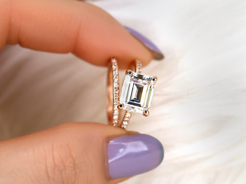 east west set emerald cut solitaire with diamonds on shank and matching diamond band pinched between 2 fingers