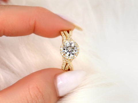 14kt gold moissanite bridal ring with round halo and diamond-accented crossover band held between fingers