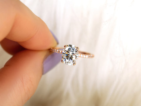 oval solitaire with diamond accents pinching between finger