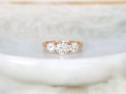 Rose gold ring with three moissanites on a soft white background