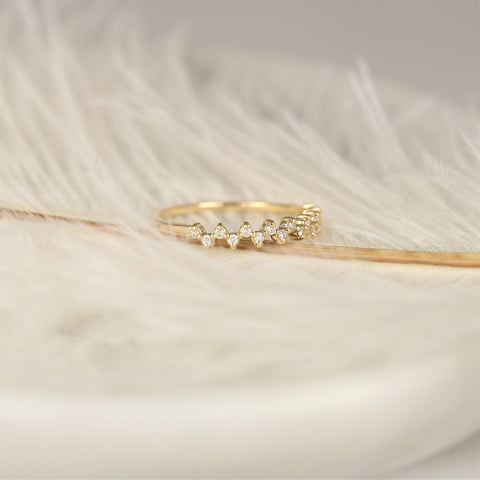 Delicate 14kt gold halfway eternity ring with small diamonds resting on soft white feathers background