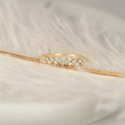 Delicate 14kt gold diamond halfway eternity ring resting on soft white feathers with a warm neutral background
