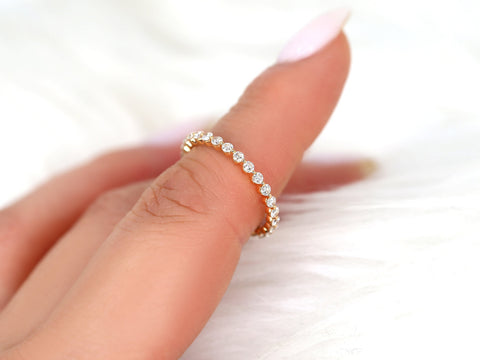 Close-up of a delicate rose gold diamond band with small round stones worn on a finger against soft white background