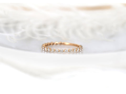 Delicate rose gold slim band adorned with small diamonds in an almost eternity style on soft white fabric background