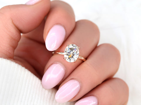 Hand wearing a rose gold engagement ring with a large oval lab grown diamond and pale pink nails