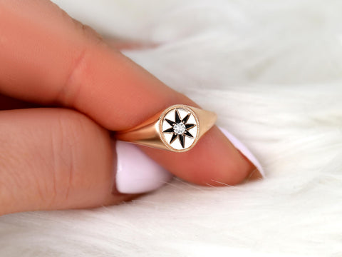 Rose gold ring featuring a star design with a central diamond held between fingers on a soft white background