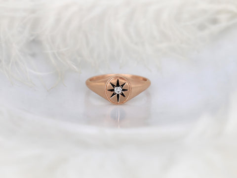 Rose gold ring featuring a starburst design with a central diamond on a soft white background