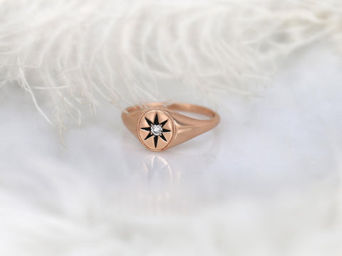 Rose gold ring with a star motif and small center diamond displayed on a soft white feather background