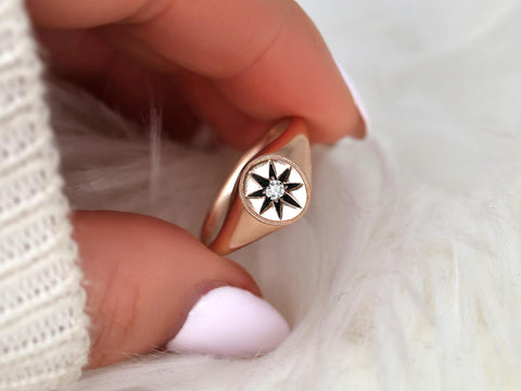 Close-up of rose gold ring featuring a star design with a central diamond held between fingers on soft white background