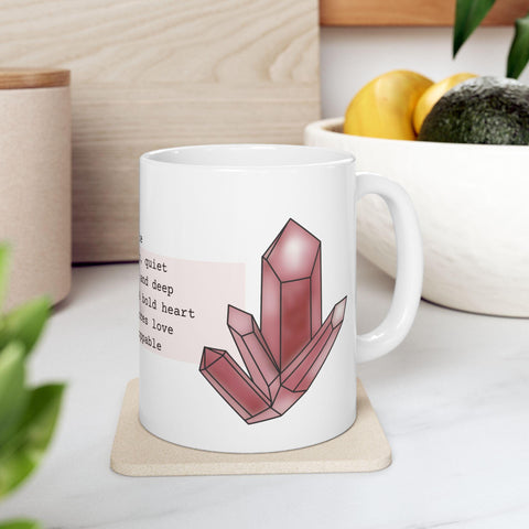 White ceramic mug with pink crystal cluster illustration and poetic text on a kitchen countertop setting