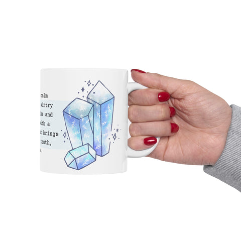 Hand holding white mug featuring blue crystal illustrations with a calm wintery theme and red polished nails