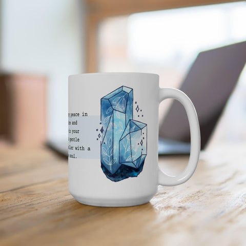 White ceramic mug displaying a blue crystal illustration with delicate leaf patterns on a wooden table surface