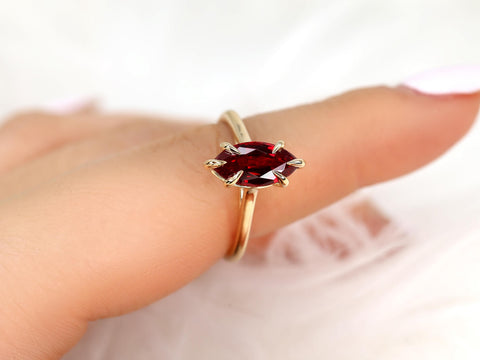 Delicate 14kt gold ring with marquise-shaped deep red ruby solitaire on a slender band close-up on finger