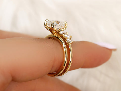 Stacked 14kt gold bridal set featuring oval moissanite solitaire with smaller side stones on hand close-up