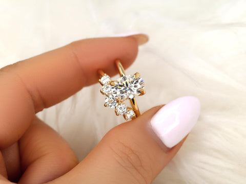Hand holding a 14kt gold bridal set featuring an oval moissanite solitaire with accent stones on a soft background