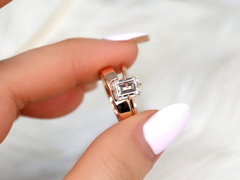 Hand holding a 14kt gold emerald cut moissanite solitaire bridal set ring with a sleek polished band