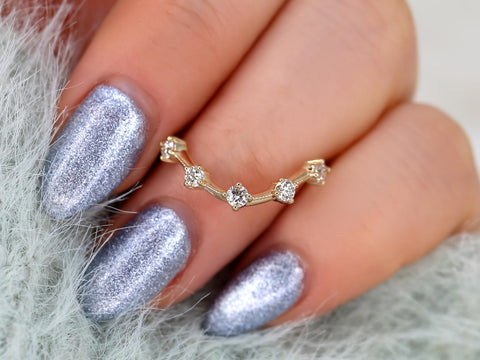 Delicate 14kt gold ring with five small diamonds in a unique curved design worn on finger with silver nail polish