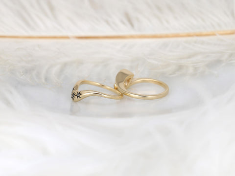 Two delicate 14kt gold rings on soft white feathers, one featuring a star pattern detail, bridal set style