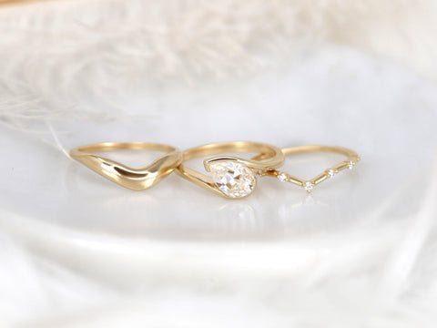 Three delicate 14kt gold rings including a tilted pear moissanite solitaire and two slim bands with small diamonds