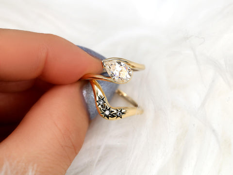 14kt gold bridal ring set with a tilted pear-shaped moissanite and engraved star details on band