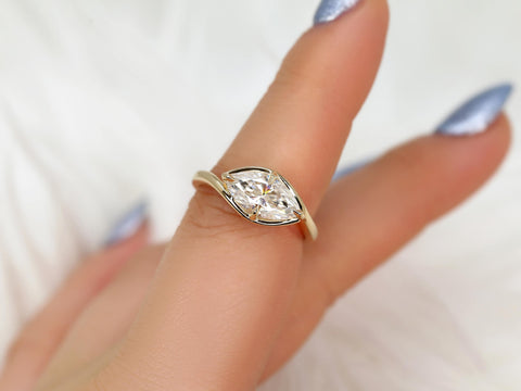 Hand wearing a marquise diamond solitaire ring set horizontally on a sleek yellow gold band, fine jewelry for engagement.