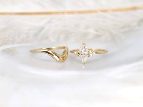 Delicate 14kt gold moissanite bridal set featuring a marquise center stone and a curved wedding band on soft white background