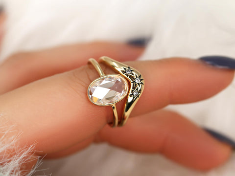 moissanite rose cut oval ring paired with a three diamond celestial curved band in gold on finger