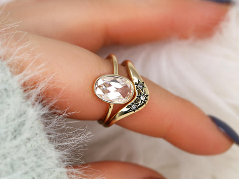 moissanite rose cut oval ring paired with a three diamond celestial curved band in gold on finger