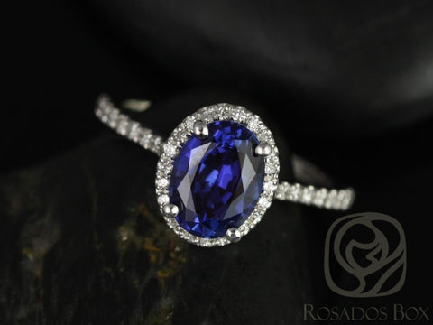 Close-up of oval blue sapphire ring with diamond halo and diamond band on dark textured background