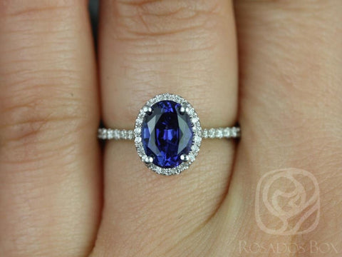 Oval blue sapphire ring with diamond halo and delicate white gold band worn on finger