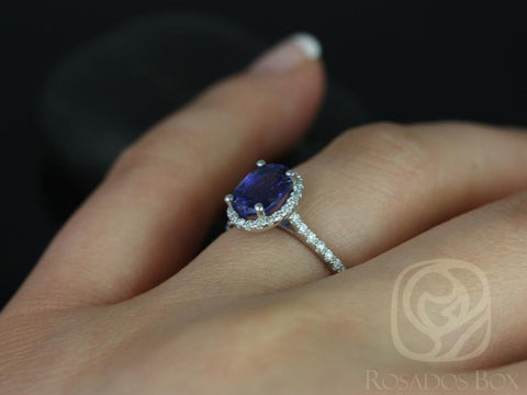 14kt white gold ring with oval blue sapphire center stone surrounded by diamond halo on a finger