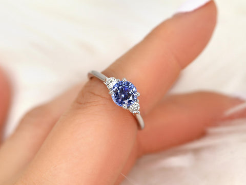 cornflower blue sapphire three stone ring on pointer finger and white background