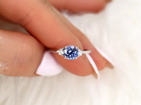 cornflower blue sapphire three stone ring between finger and white background