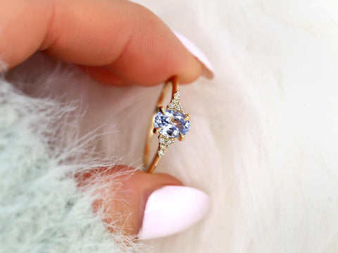 oval cornflower lilac sapphire cluster ring with dainty diamonds held between fingers