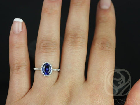 14kt gold ring featuring oval blue sapphire center surrounded by diamond halo on finger against black background