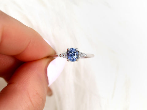 oval cluster ring with cornflower sapphire center stone pinched between finger