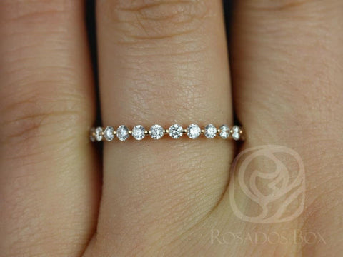 Close-up of a delicate rose gold diamond ring featuring small round diamonds in an almost eternity style on a finger