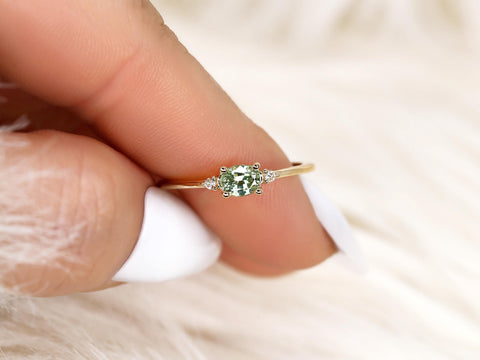 oval green sapphire ring in trilogy style with two diamonds on yellow gold on pointer finger