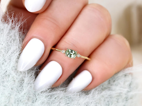 oval green sapphire ring in trilogy style with two diamonds on yellow gold on ring finger