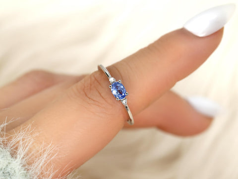 oval cornflower blue sapphire ring in trilogy style with two diamonds on white gold on pointed finger