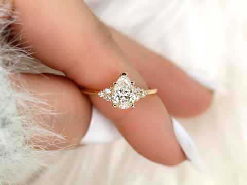 pear cut diamond ring with cluster diamonds on a finger