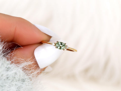 oval green sapphire ring in three stone with two diamonds on yellow gold presented pinching