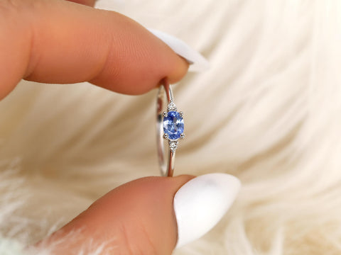 oval cornflower blue sapphire ring in trilogy style with two diamonds on white gold on between fingers