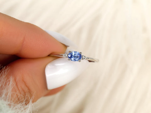 oval cornflower blue sapphire ring in trilogy style with two diamonds on white gold on pinching
